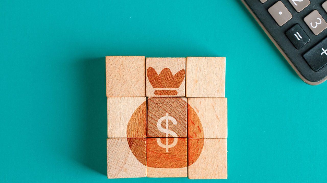 Financial concept with icon on wooden cubes, calculator on turquoise background flat lay.