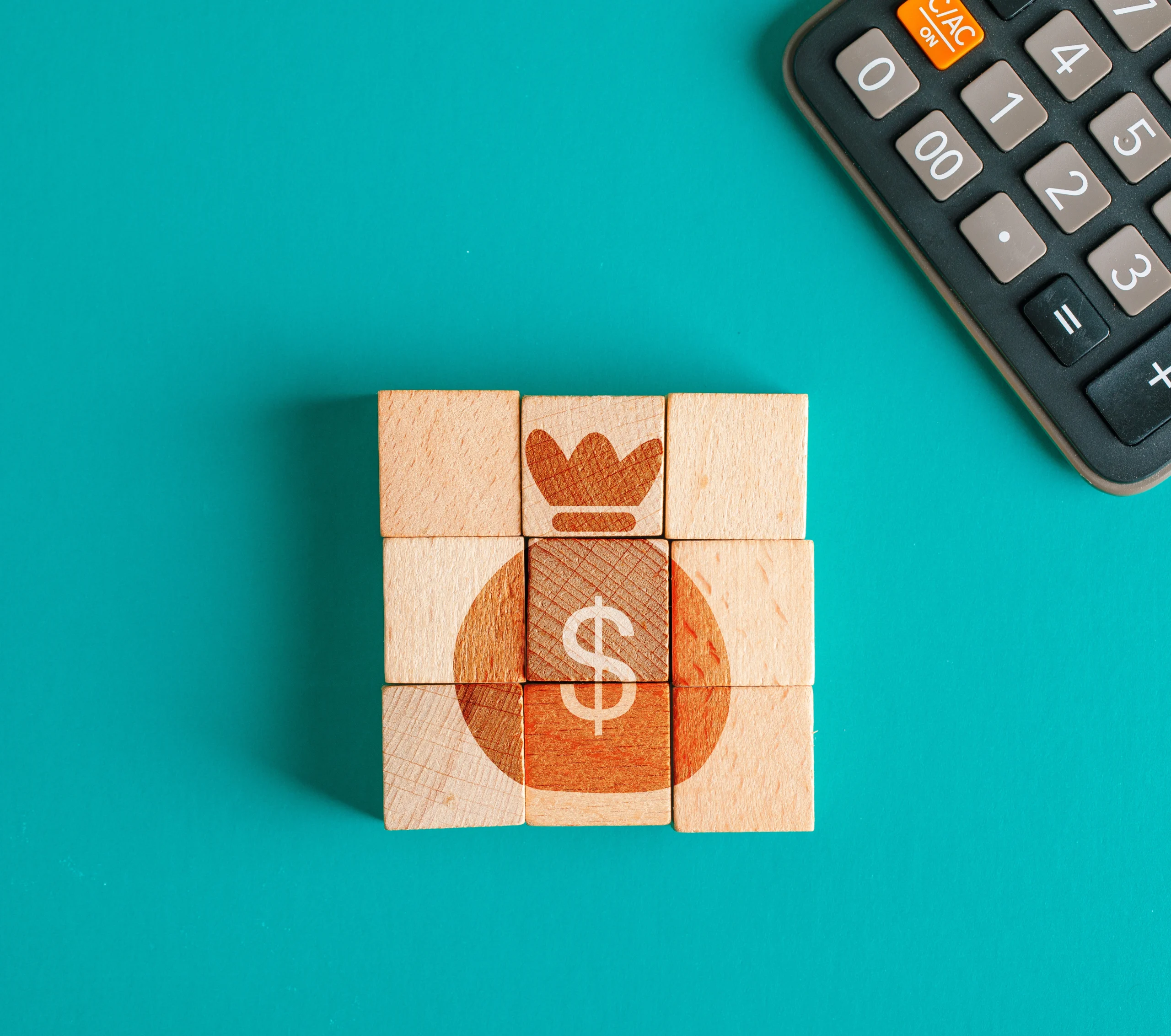 financial-concept-with-icon-wooden-cubes-calculator-turquoise-table-flat-lay-scaled