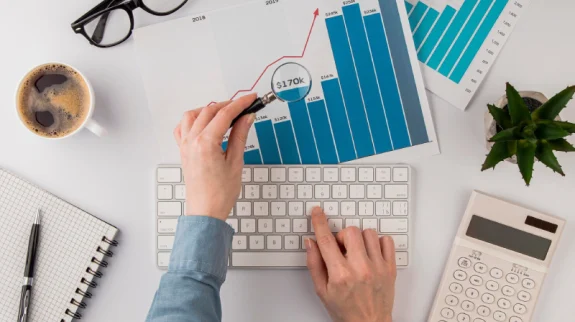 top-view-office-desk-with-growth-chart-analyzed-with-magnifying-glass_23-2148780618