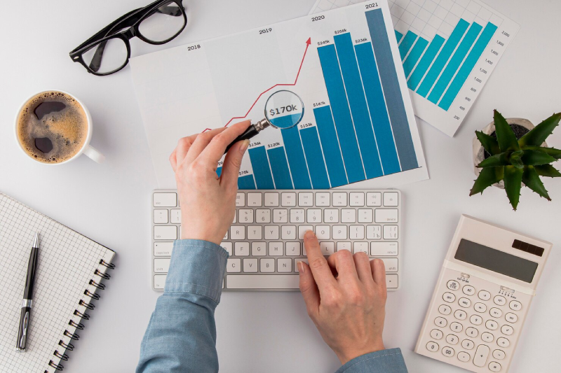 top-view-office-desk-with-growth-chart-analyzed-with-magnifying-glass_23-2148780618